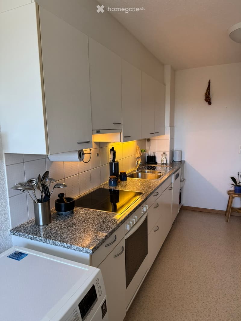 Modern kitchen with white cabinets, granite countertop, stainless steel appliances, and built-in lighting. Features a microwave, oven, sink, and various kitchen utensils.