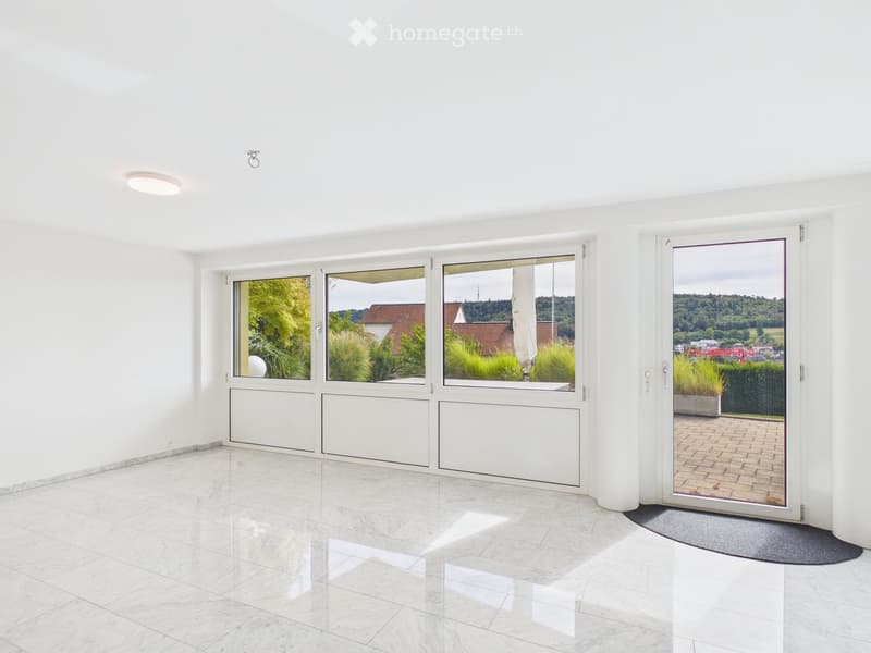 Bright, empty room with white walls, marble flooring, large windows, and a sliding glass door leading to an outdoor area.