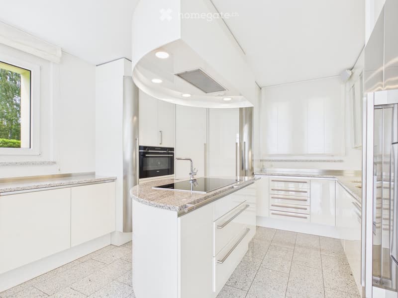 Modern white kitchen with granite countertops, stainless steel appliances, and ample cabinetry.