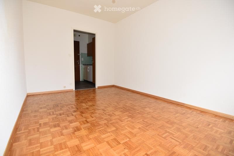Completely empty room with bare white walls and a polished wooden floor. No furniture or equipment.