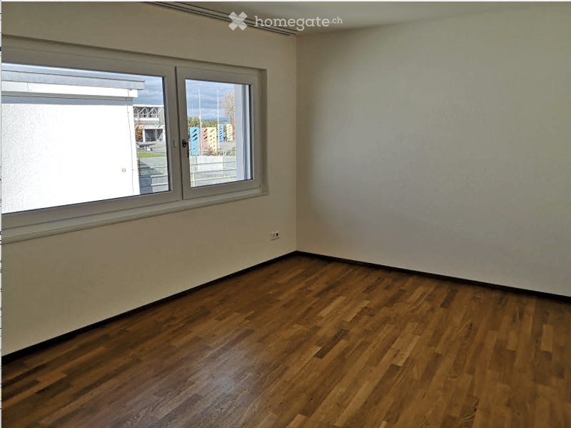 Empty room with wooden flooring and large windows, no furniture or equipment.