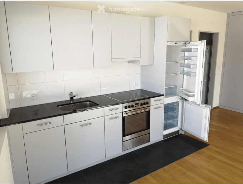 Modern kitchen with white cabinets, stainless steel appliances, and a black countertop.