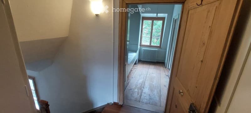 Empty room with wooden flooring, a window, and a radiator. No furniture or equipment is present.