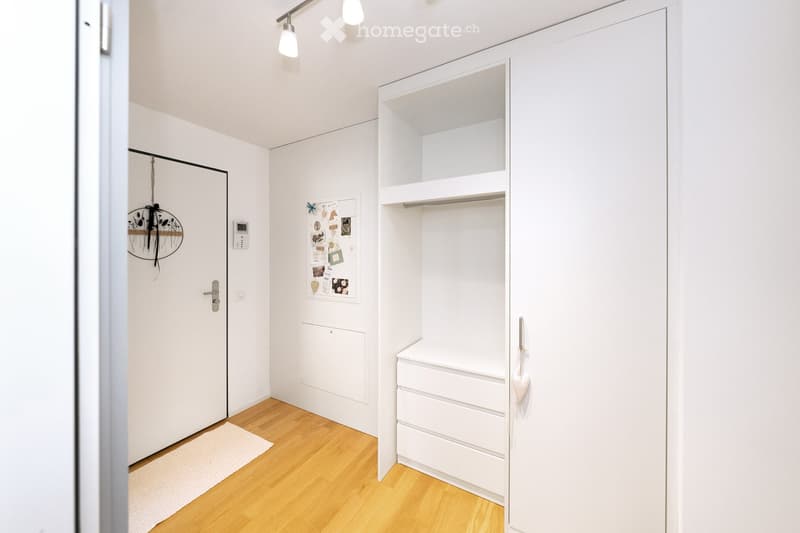 Empty room with white walls, wooden floor, built-in closet with shelves, and a small white chest of drawers. No furniture or personal items present.