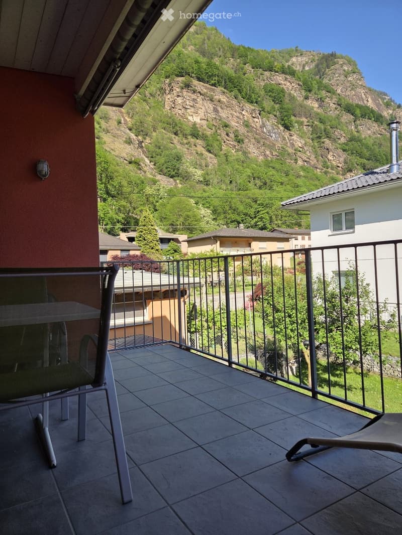 Balcony with tiled floor, metal railing, and scenic mountain view. Includes a table and chairs.