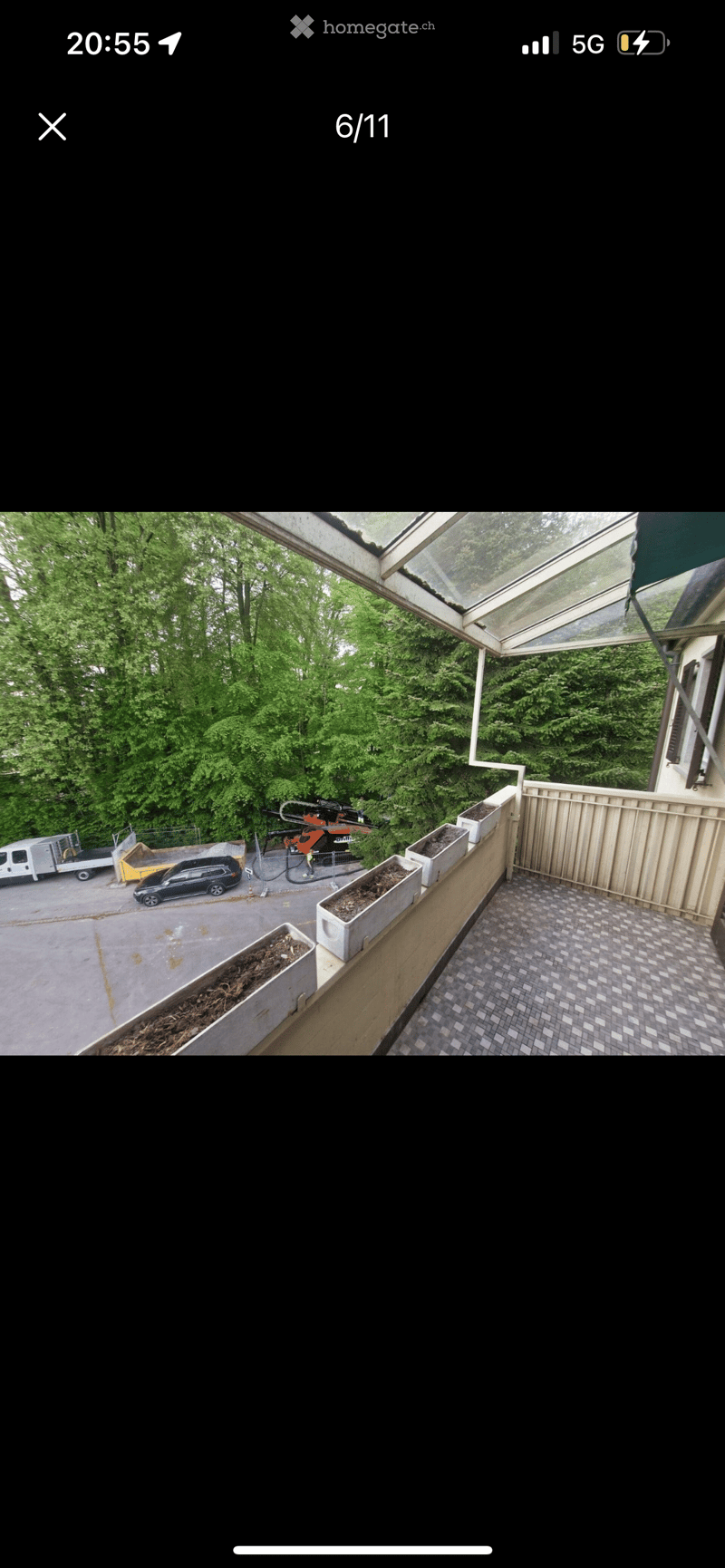 Balcony terrace with a view of a forested area, plants in containers, and paved floor