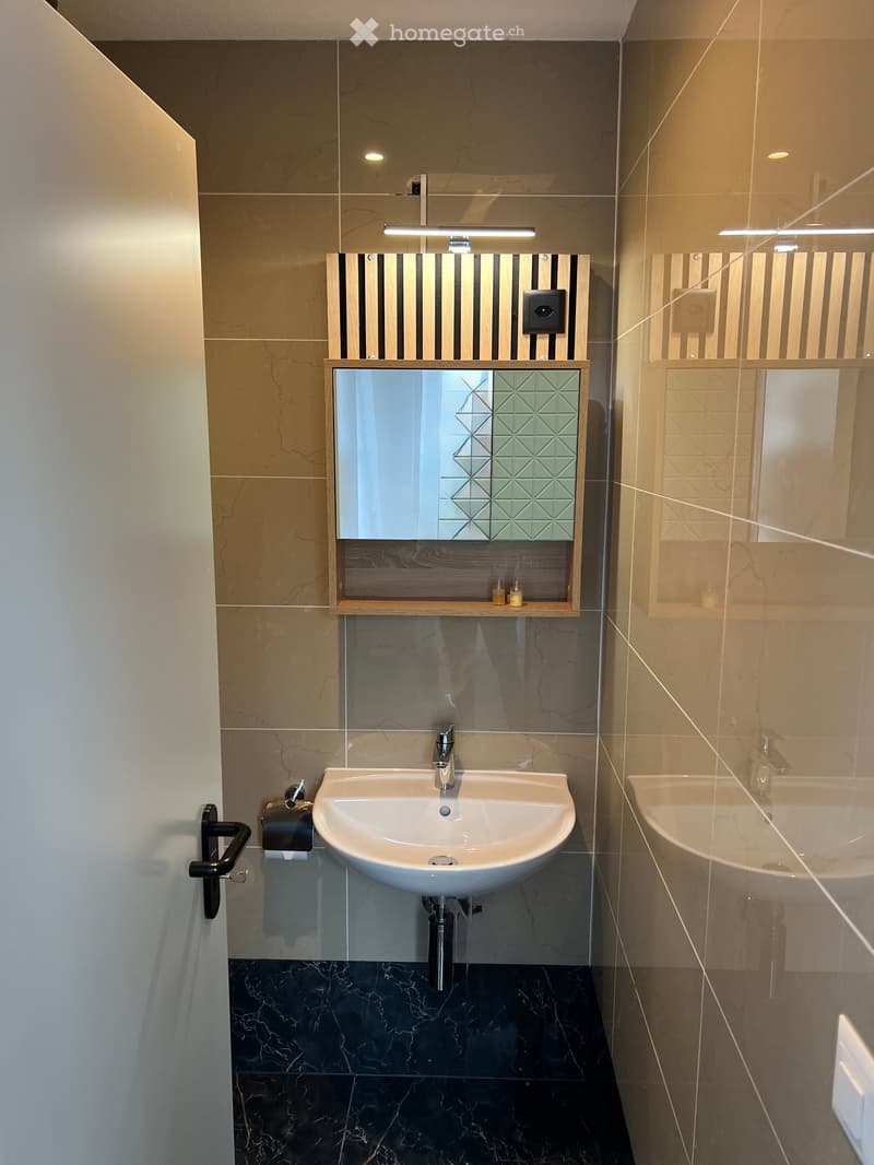 small bathroom with tile walls, white countertop, white sink, mirror above sink