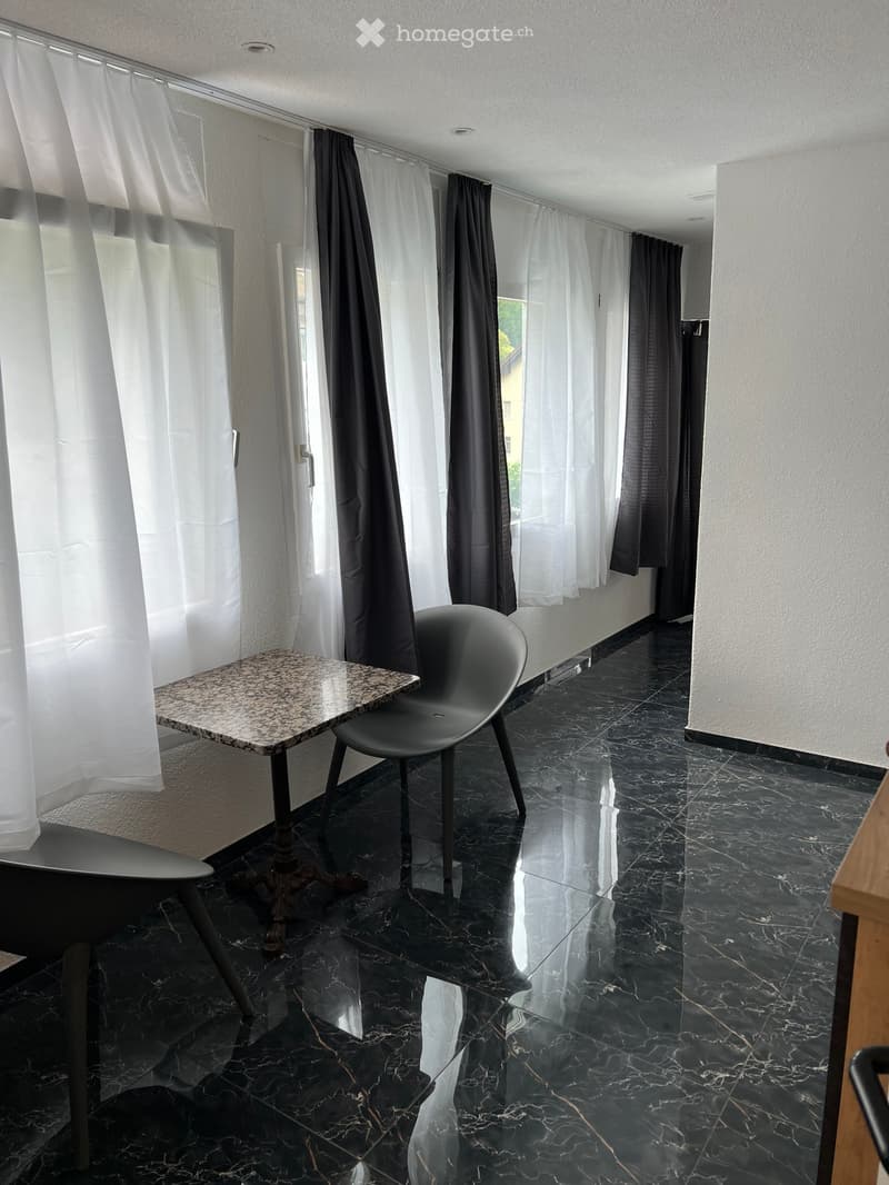 a room with chairs and a small table by the window, shiny marble flooring