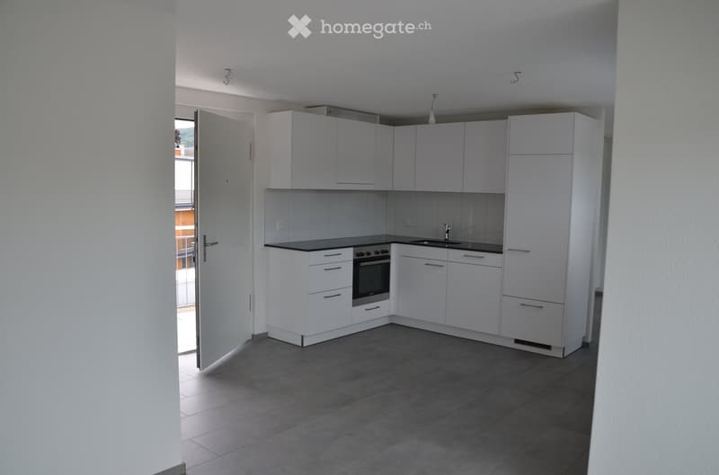 Modern kitchen with white cabinets, black countertops, and stainless steel appliances including an oven and sink.