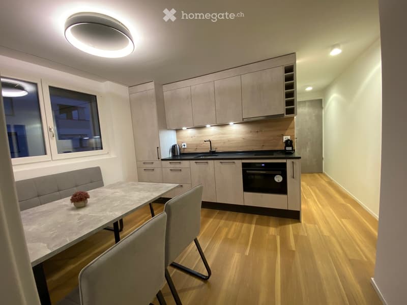 kitchen with dining table, grey sofa, grey chairs, large window, built-in appliances