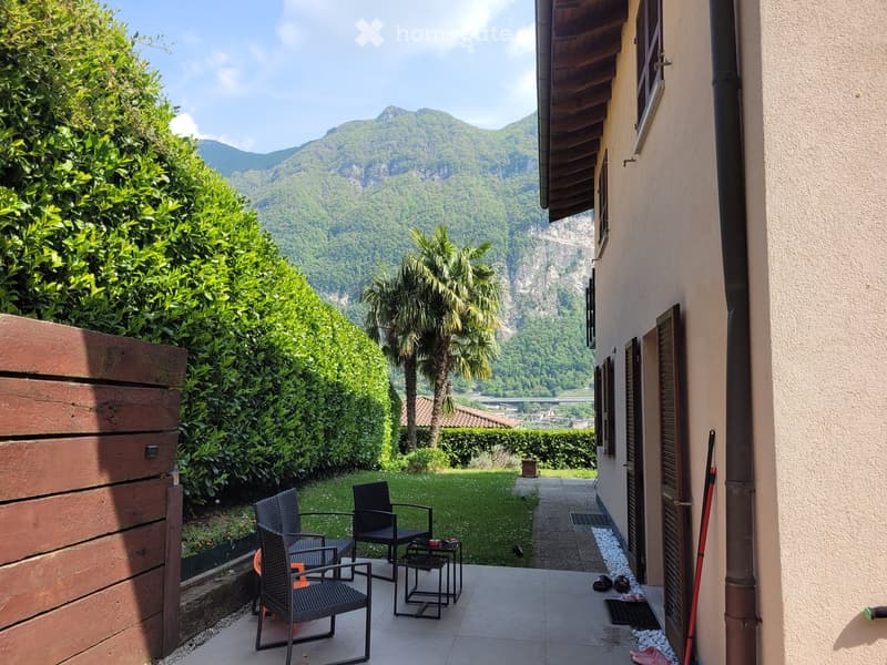 Balcony with outdoor furniture, overlooking a scenic valley with mountains and greenery.