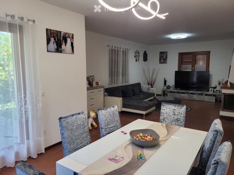 Living room with a sofa, coffee table, dining table with chairs, and a television. The room features a modern design with a mix of contemporary and classic elements.