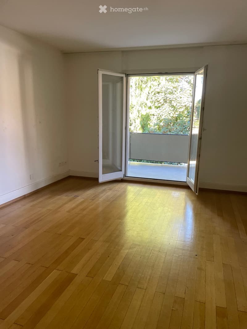 Empty room with wooden flooring and large sliding glass doors leading to a balcony or terrace area.