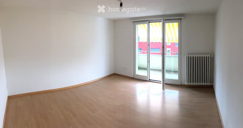 Empty room with wooden flooring, white walls, and a sliding glass door leading to a balcony.