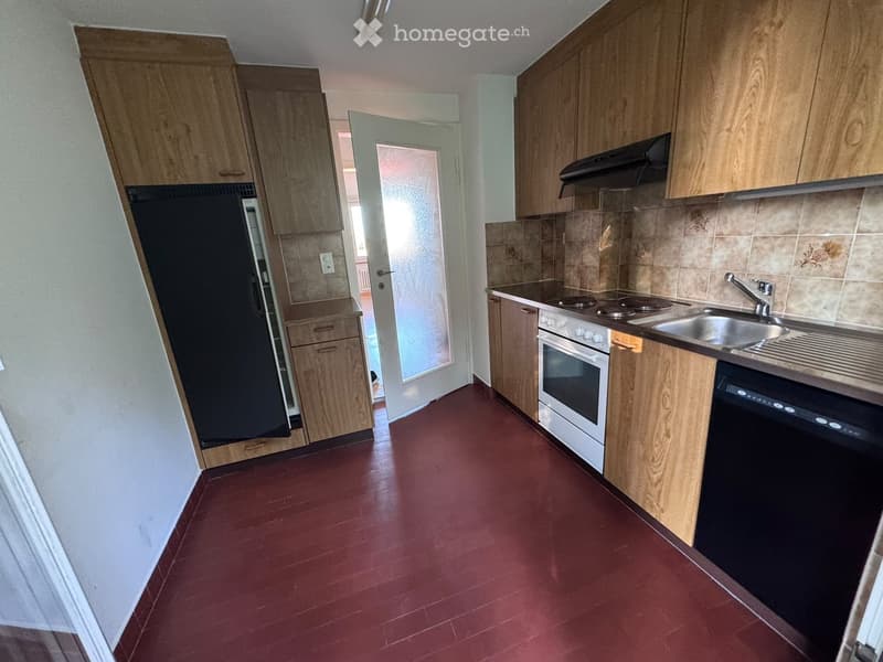 Kitchen with wooden cabinets, red floor, refrigerator, oven, dishwasher, sink, and faucet.