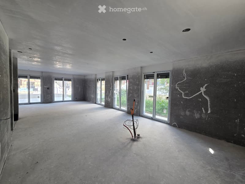 Empty room with concrete floors and walls, large windows, and a small decorative stand in the center.