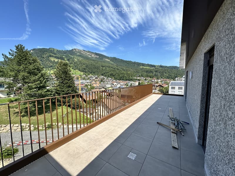 Balcony with tiled floor, wooden railing, and scenic mountain and town view.
