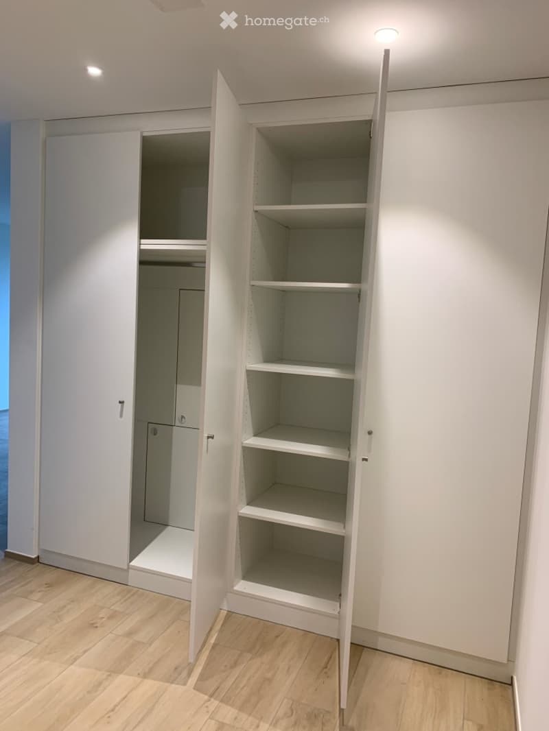 Empty room with white built-in wardrobes and wooden flooring. No furniture or items present.