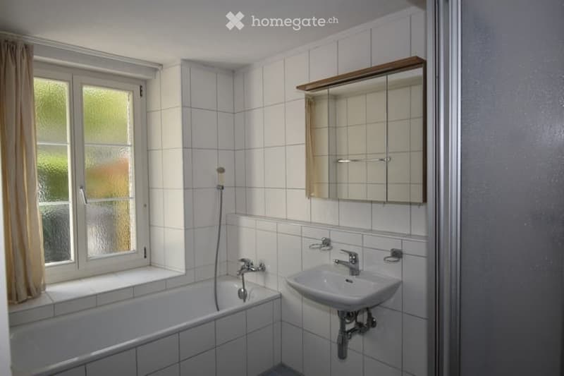Bathroom with white tiled walls, a bathtub, a sink, a mirror, and a window with a curtain.