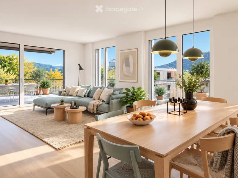 Modern living and dining area with large windows offering a scenic mountain view. Features a green sectional sofa, wooden coffee tables, a dining table with chairs, and decorative items including a vase with candles and a bowl of fruit.