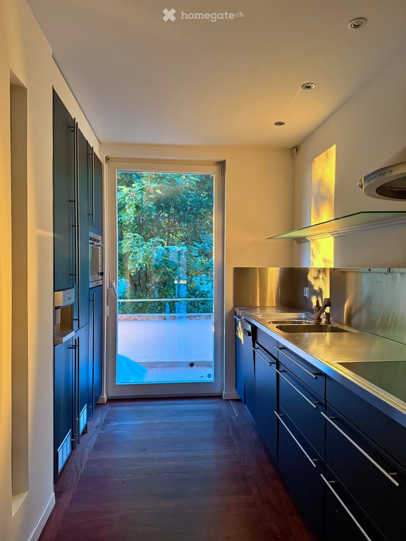 open kitchen with a glass door, large window, black cabinetry, stainless steel counters, double sink