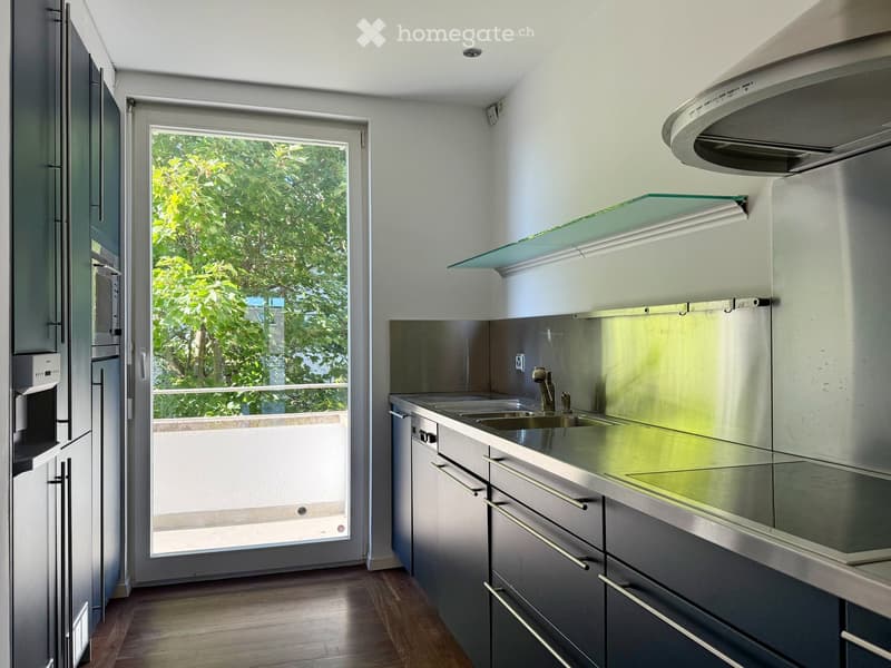 Modern kitchen, stainless steel countertops, large window, sliding door to balcony