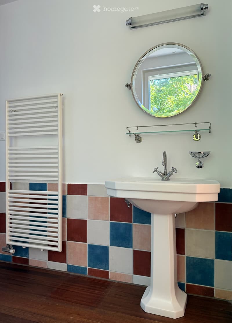 White sink, faucet, mirror, white heater, tile flooring