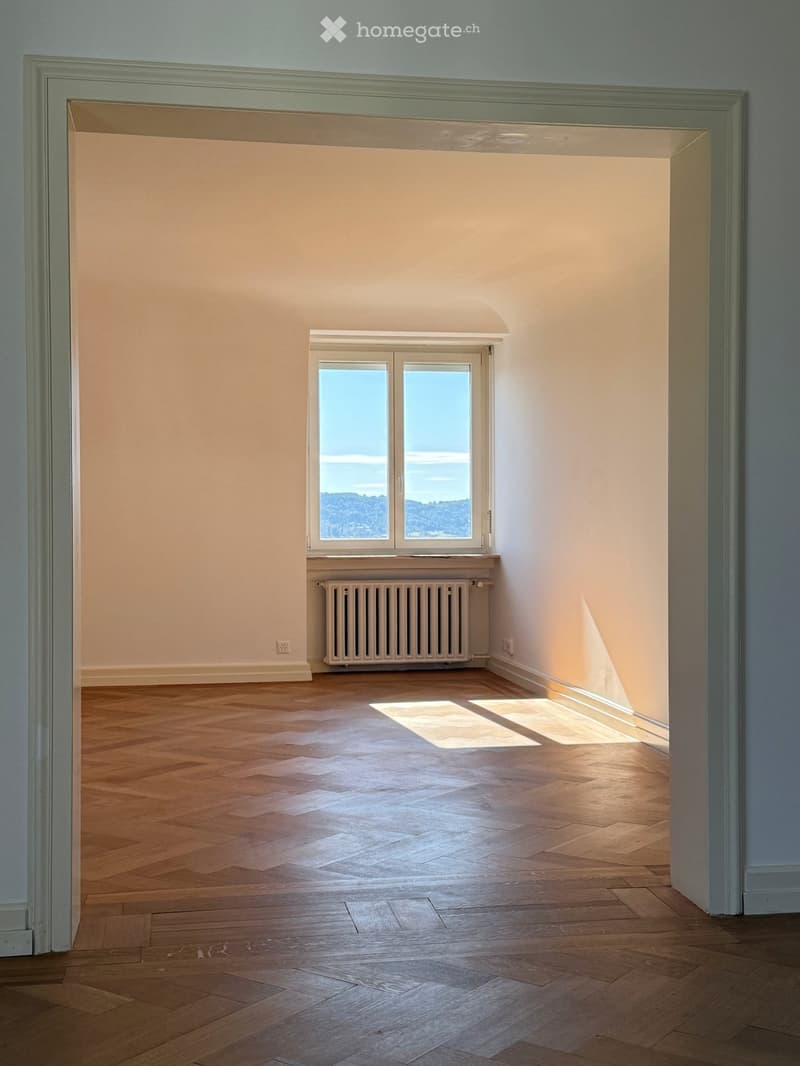 empty room with wooden floors, white walls, radiator and a large window with view