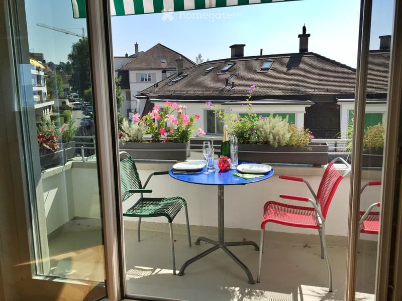 table, chairs, flowers, wine, wine glasses, balcony, glass doors, balcony railing, plants, view of a street