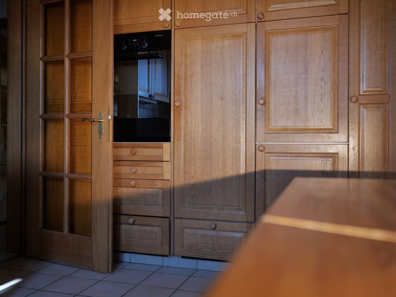 Wooden kitchen with built-in oven, multiple cabinets, and drawers.