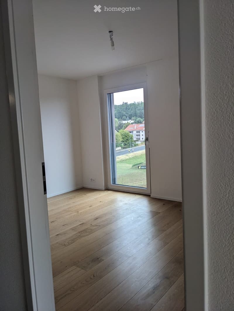 Empty room with wooden flooring, white walls, and a large sliding glass door leading to an outdoor view.