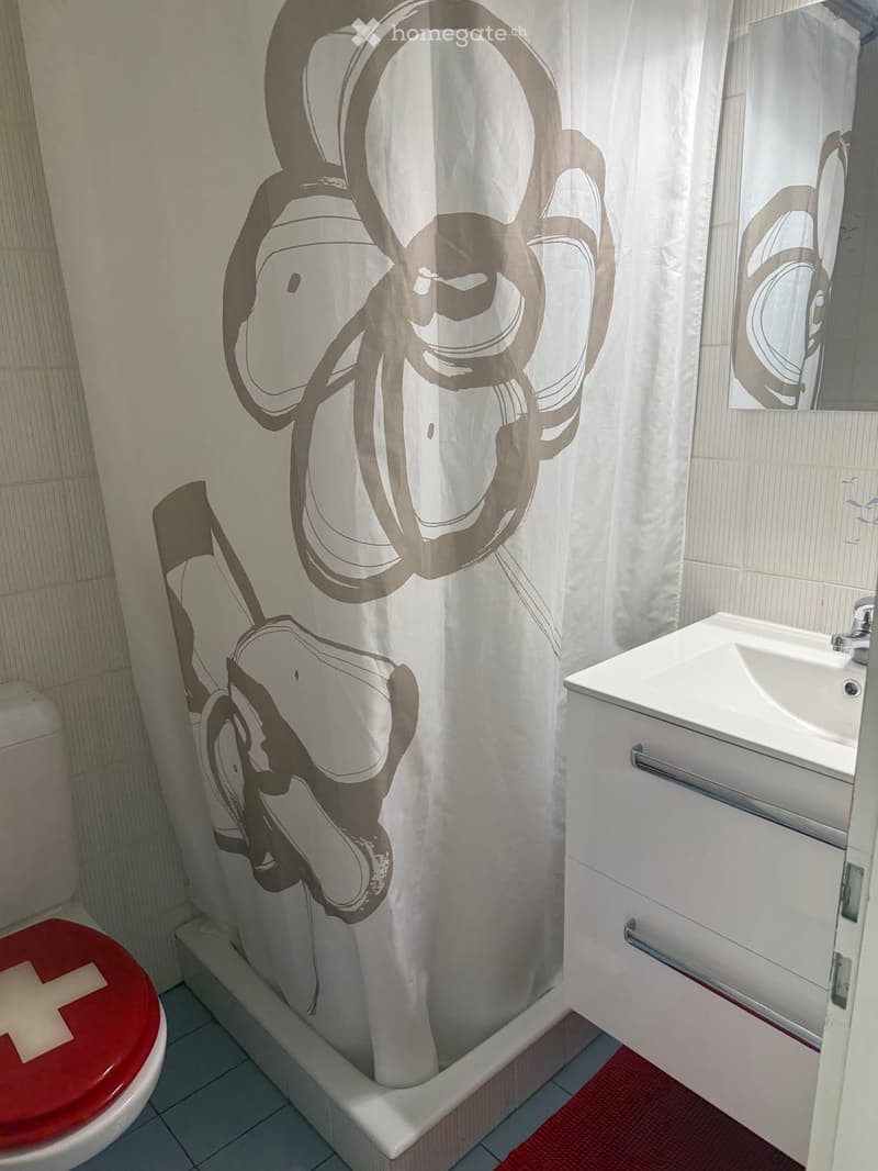 Bathroom with a toilet, sink, mirror, and a shower curtain with a modern abstract design.
