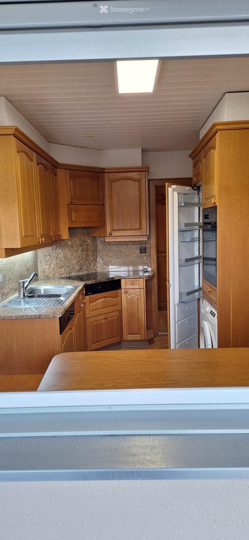 Modern kitchen with wooden cabinets, granite countertops, stainless steel sink and faucet, and built-in appliances including a refrigerator, oven, microwave, and dishwasher.