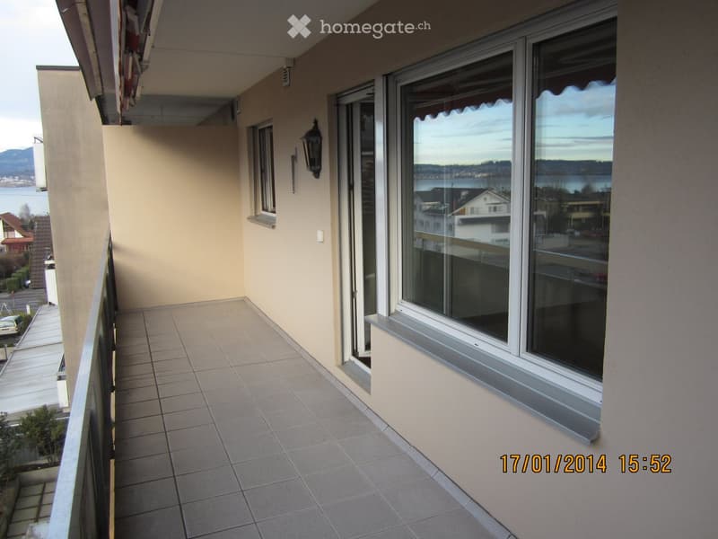 Balcony with tiled floor, large windows, and a view of the water and surrounding buildings.