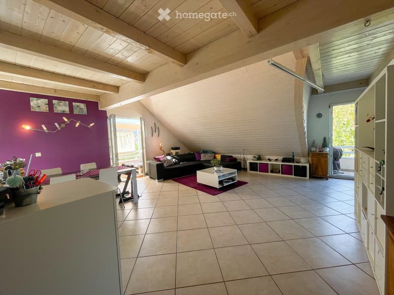Bright living room with exposed wooden beams, purple accent wall, and large windows. Features a black sectional sofa, white coffee table, dining area with chairs, and built-in storage units.