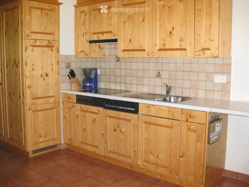 A kitchen with wooden cabinets, a sink, a dishwasher, a coffee maker, and a knife block.