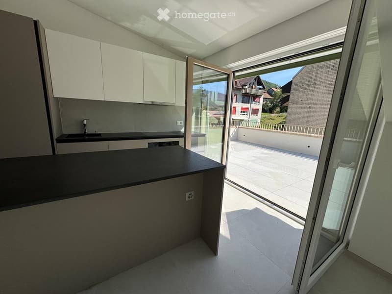 Modern kitchen with white cabinets, black countertop, and a large window offering a view of the outdoor area.