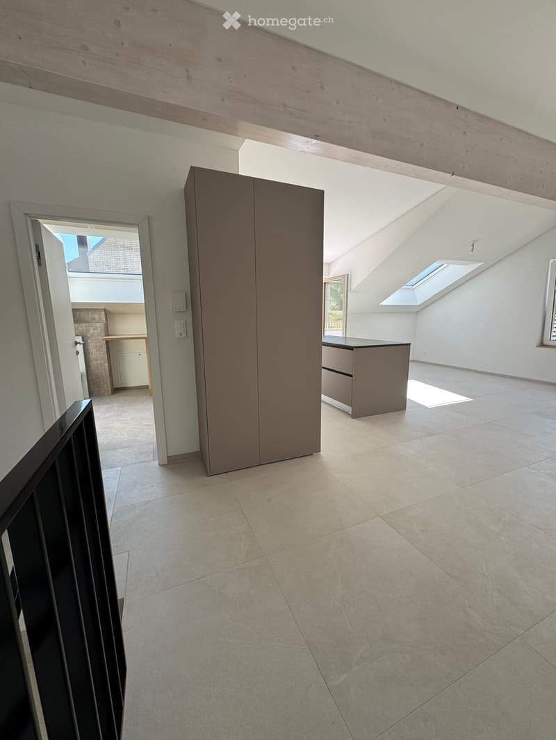 Empty room with tiled floor, white walls, and modern cabinetry. Features skylights and an open doorway leading to another room.