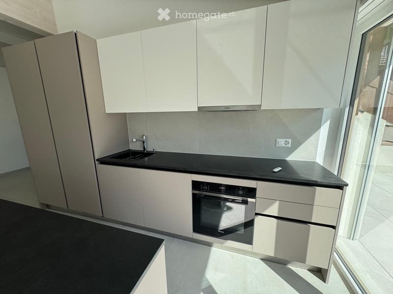 Modern kitchen with white cabinets, black countertops, and built-in oven. Features a sink with a modern faucet and ample storage space.