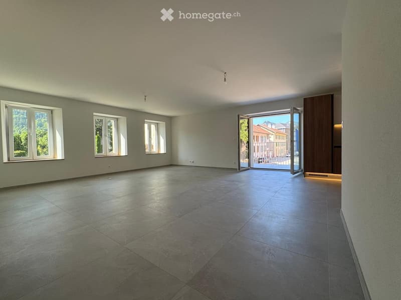 Empty room with tiled floor, large windows, and an open sliding door leading to a balcony.
