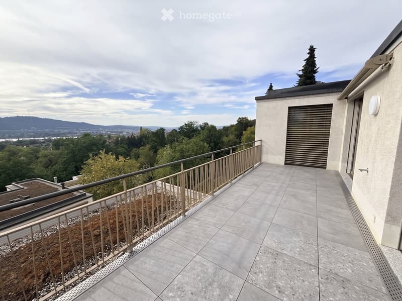 Balcony with tiled floor, metal railing, and scenic view of trees and distant landscape.