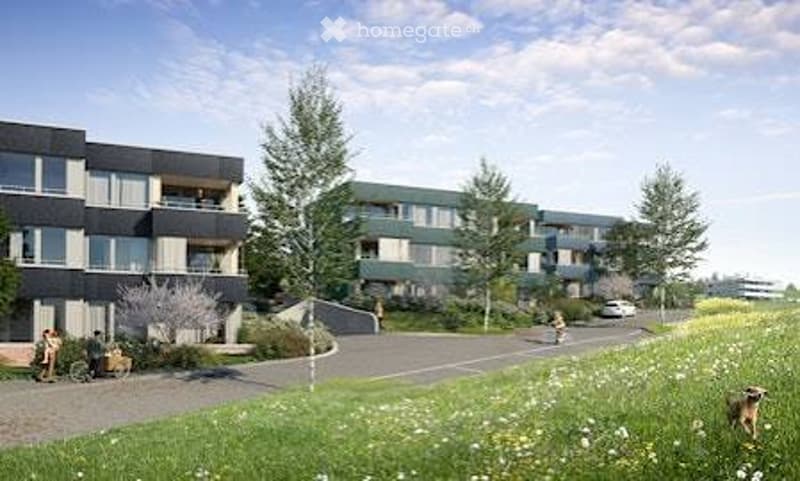 Modern multi-story residential building with balconies, surrounded by greenery and a paved pathway.