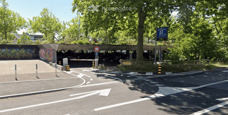 Parking area with a covered section, trees, and a parking sign.