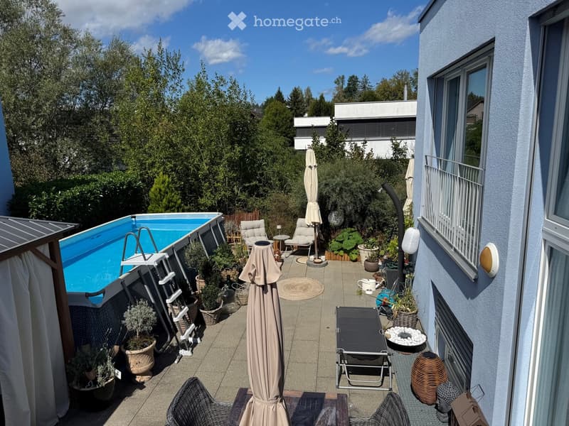 Outdoor patio with swimming pool, lounge chairs, umbrella, potted plants, and sun lounger.