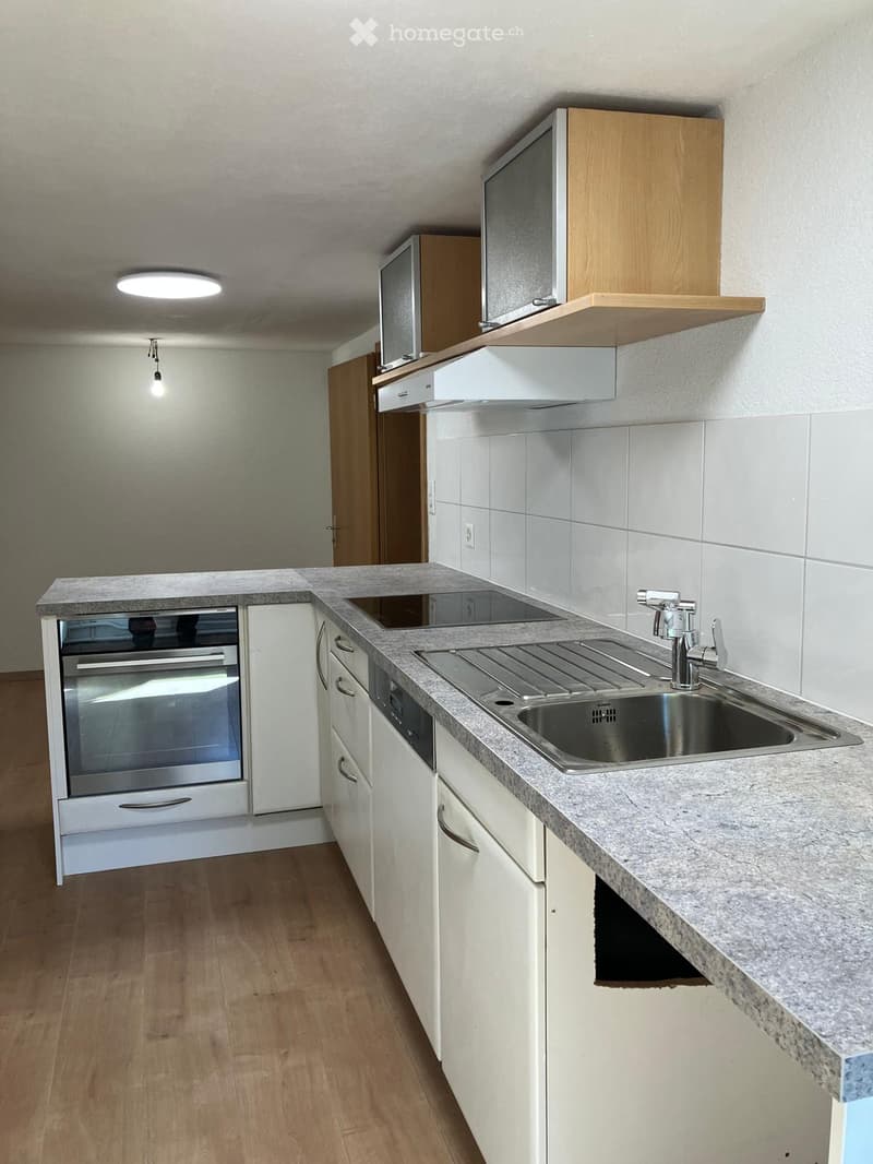 Modern kitchen with white cabinets, granite countertop, stainless steel sink, and built-in oven. Features wooden flooring and recessed lighting.