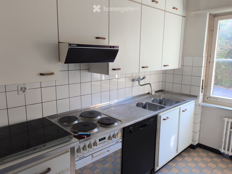 Modern kitchen with white cabinets, stainless steel appliances, and a tiled backsplash.
