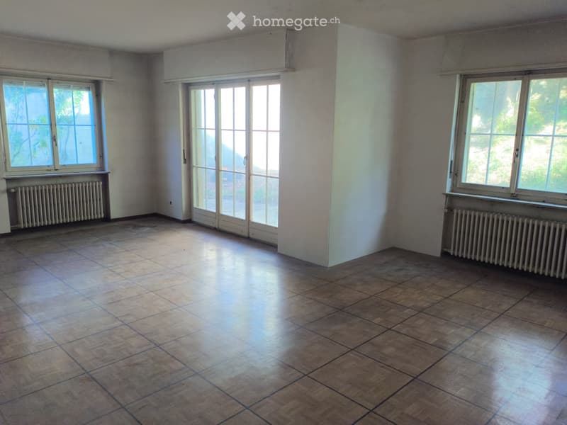 Empty room with tiled floor, large windows, and radiators along the walls.