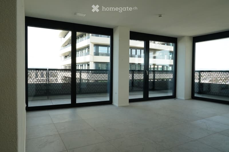 Empty room with large sliding glass doors leading to a balcony, tiled floor, and modern interior design.