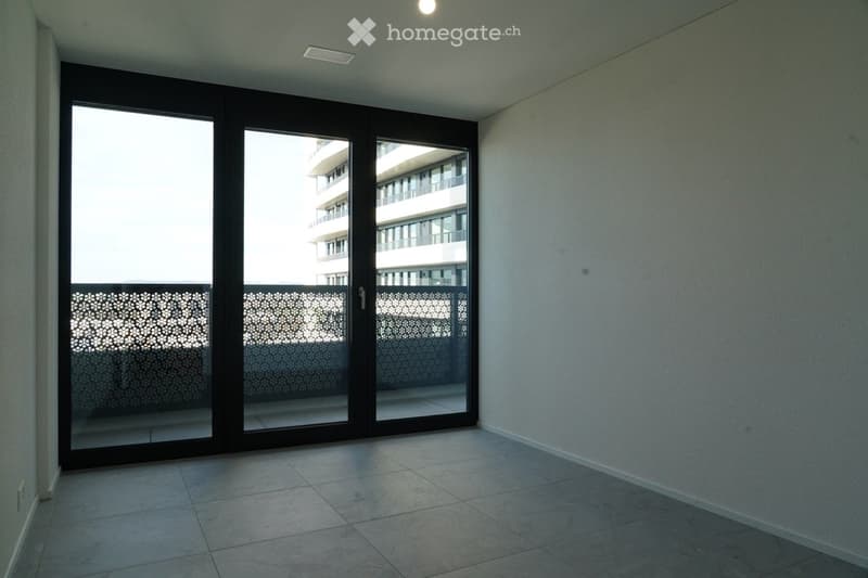 Empty room with tiled floor, white walls, and large sliding glass doors leading to a balcony.