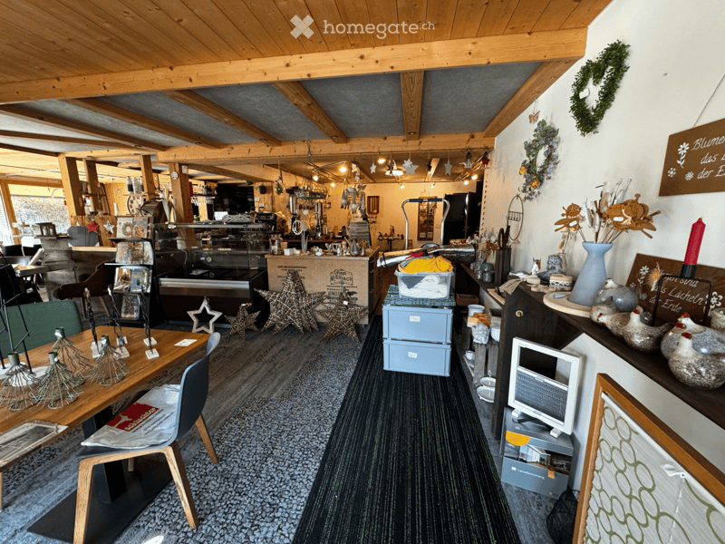 A cozy, rustic interior with wooden beams, a mix of modern and traditional decor, including a table with chairs, decorative vases, candles, and a small screen on a stand.